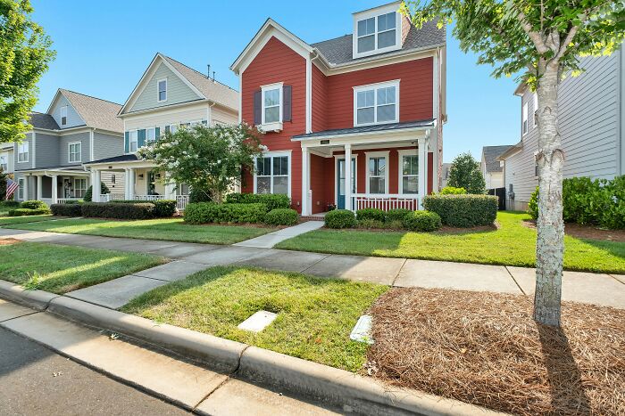 A quiet suburban neighborhood street featuring a red house representing a tiny community