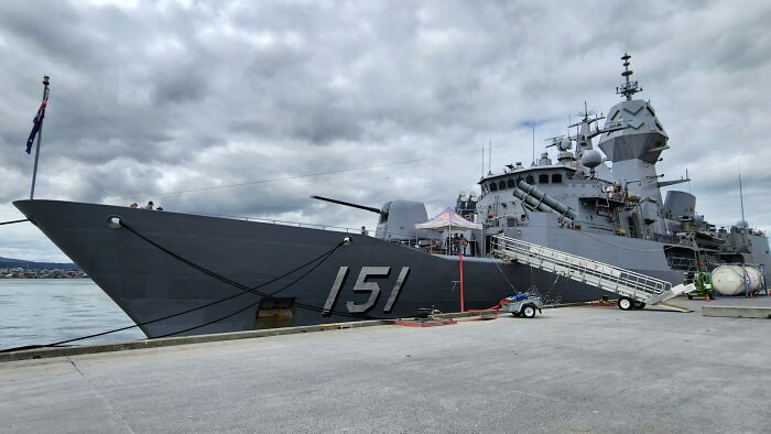 Large naval warship docked at a pier, revealing behind the scenes operations of military defense companies