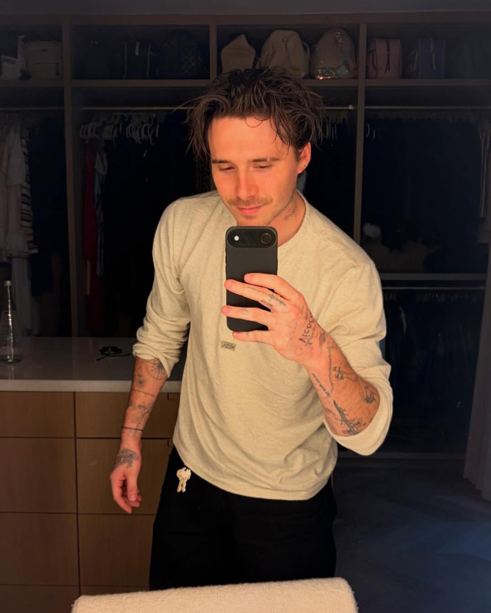 Brooklyn Beckham taking a mirror selfie showing his tattoos.