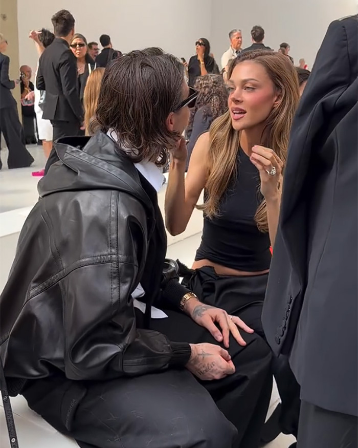 Nicola and Brooklyn Beckham talking closely in a candid moment from a viral clip during a fashion show