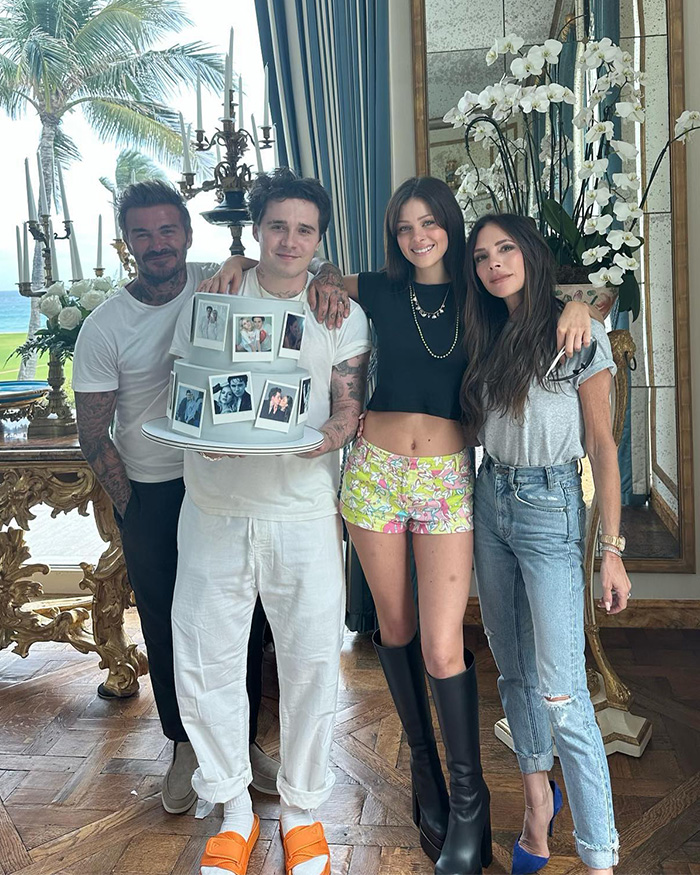 Brooklyn Beckham holding a cake next to Nicola Peltz and his parents.