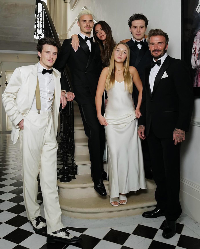 David and Victoria Beckham with their children on a staircase.