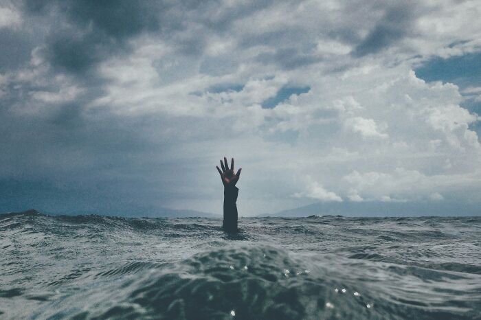 A hand reaching out from the ocean water for emergency tips on water survival