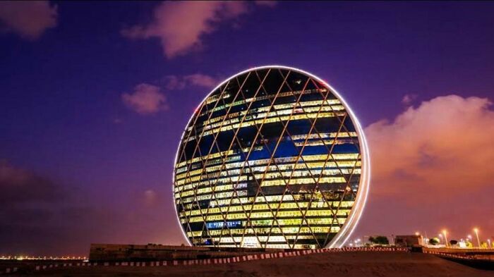 Illuminated circular building with diamond pattern lighting at night