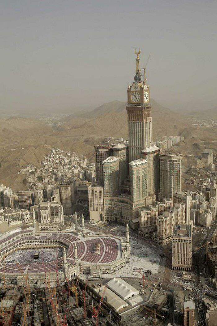 Tall clock tower with golden crescent spire overlooking city and desert