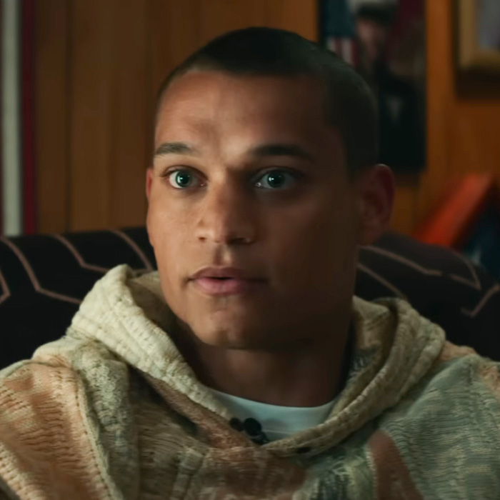 Close-up shot of a man wearing a hooded sweater indoors.