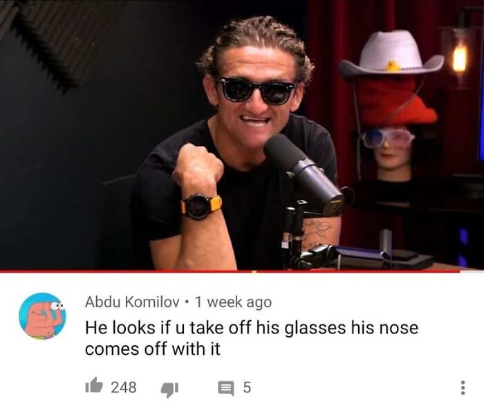 A man wearing sunglasses and a black shirt with a humorous comment about his nose and glasses
