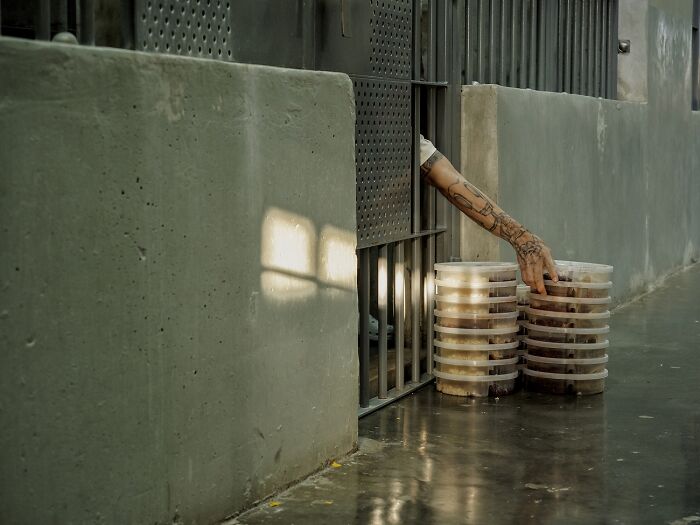 Tattooed arm reaching food containers in prison cell best pics 2026
