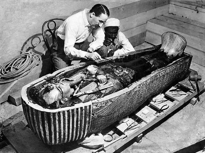 Black and white photo of archaeologists examining ancient Egyptian sarcophagus