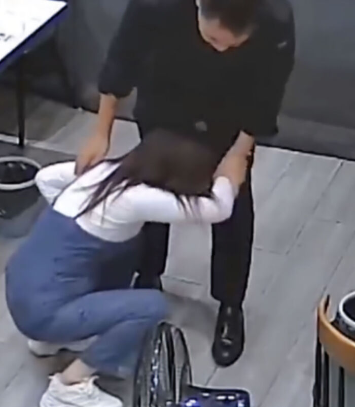 A woman bent over in pain while holding onto a man after an overly tight hug