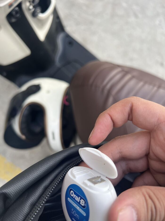 A hand holding dental floss near a scooter, featuring an example of absurd products.