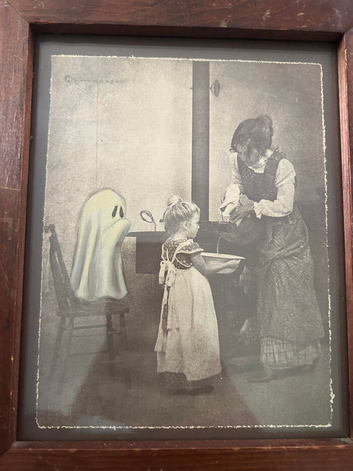 A framed vintage black and white print featuring a cute sheet ghost interacting with children for Halloween.