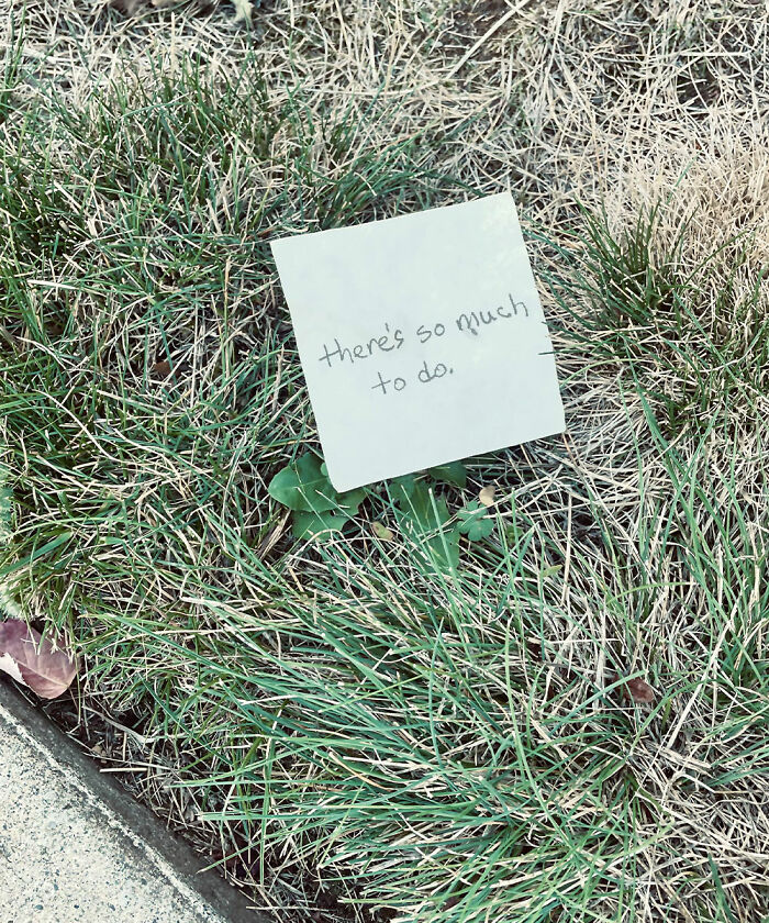 A small note resting on grass that says there is so much to do, featuring found paper.