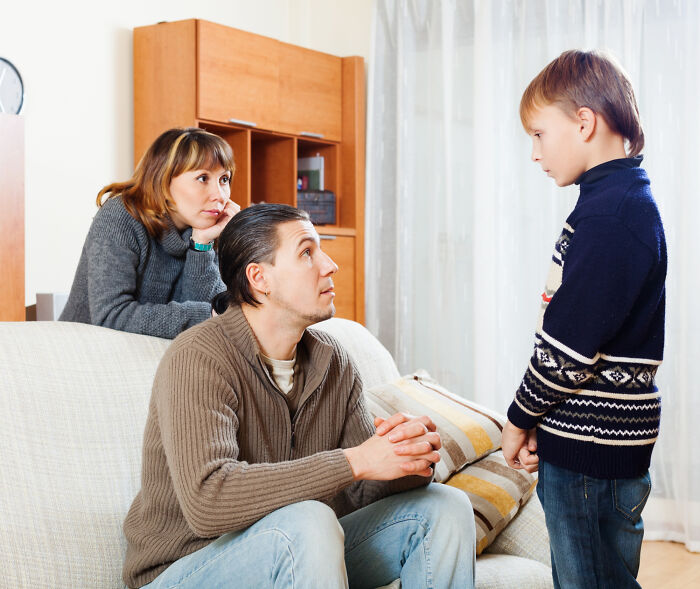 Parents sitting on a couch listening attentively to their young son, discussing how boys are raised.