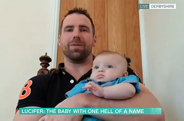 A proud father holding his baby Lucifer who became the center of a registrar naming dispute.