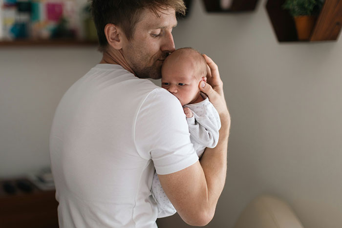 A loving father holding his baby Lucifer close, showing the bond of parents naming their child.