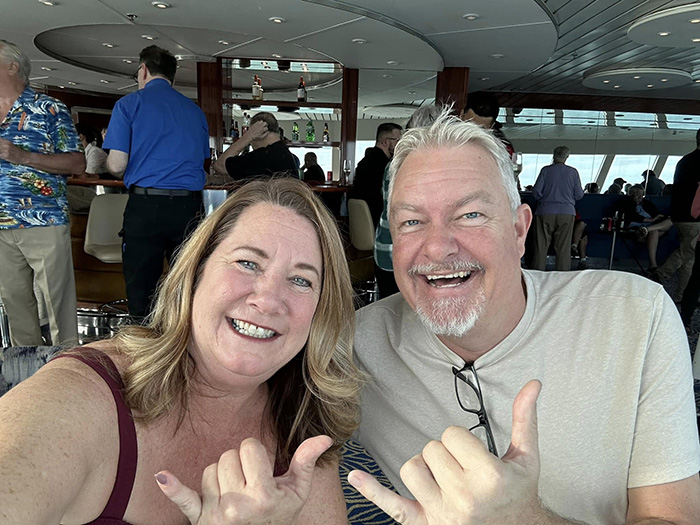 Happy passengers onboard a permanent cruise ship making hand gestures and smiling at the camera.