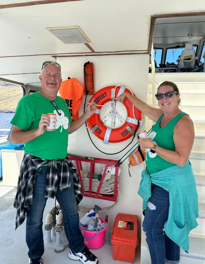 Passengers wearing green shirts posing near a life preserver ring on a permanent cruise ship deck.