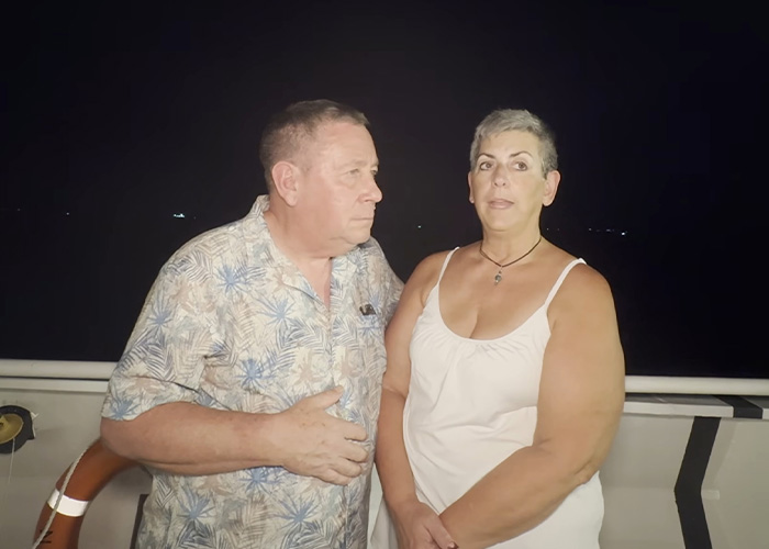 Passengers on a permanent cruise who sold their homes stand together at night.