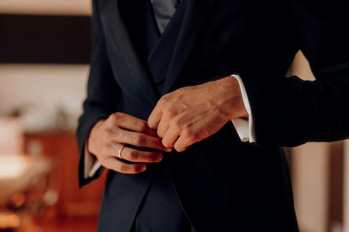 A man wearing a black suit jacket and adjusting his sleeves, representing behaviors they refuse to tolerate.