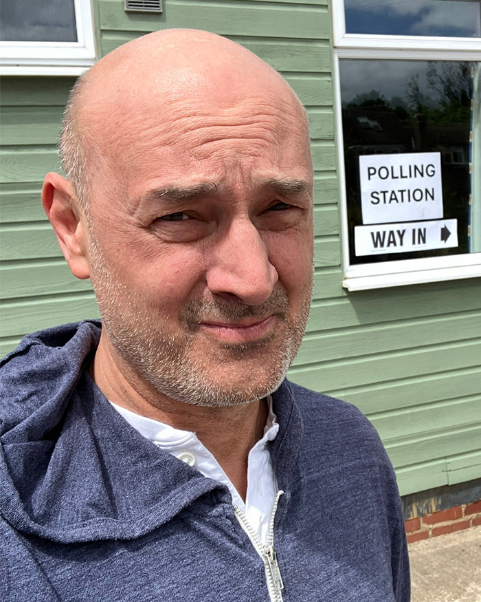 Patrick Stewart's son Daniel Stewart posing outside near a polling station.