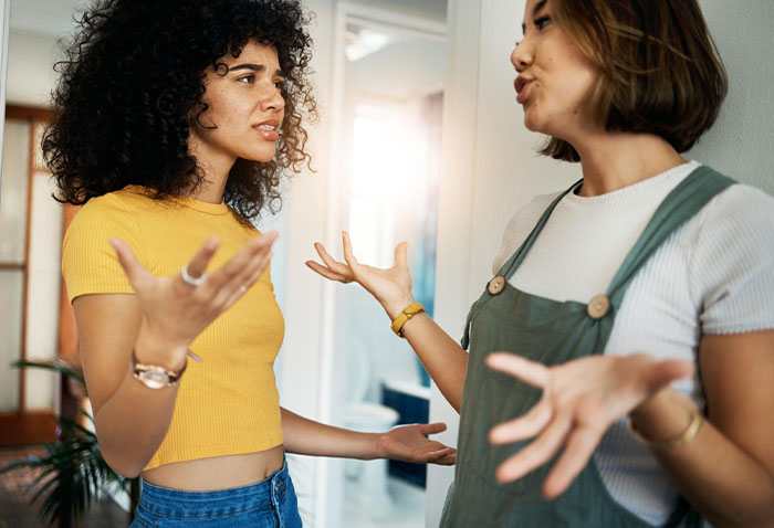 Two roommates arguing in a hallway about TV access and shared appliances Two roommates arguing in a hallway about TV access and shared appliances