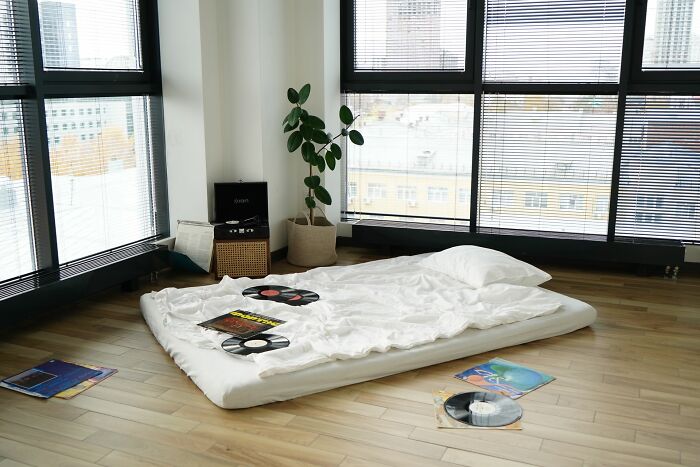 Minimalist bedroom with floor mattress and vinyl records near large windows