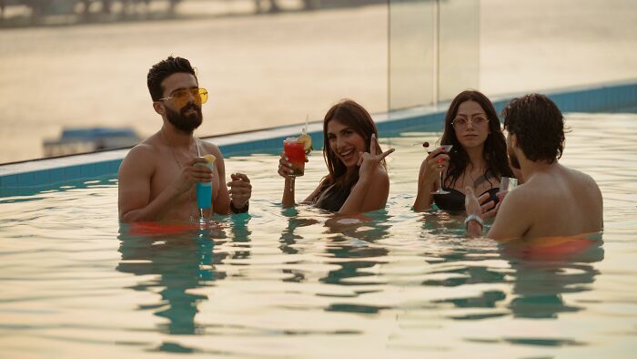A group of friends enjoying drinks in a swimming pool, related to chilling stories.