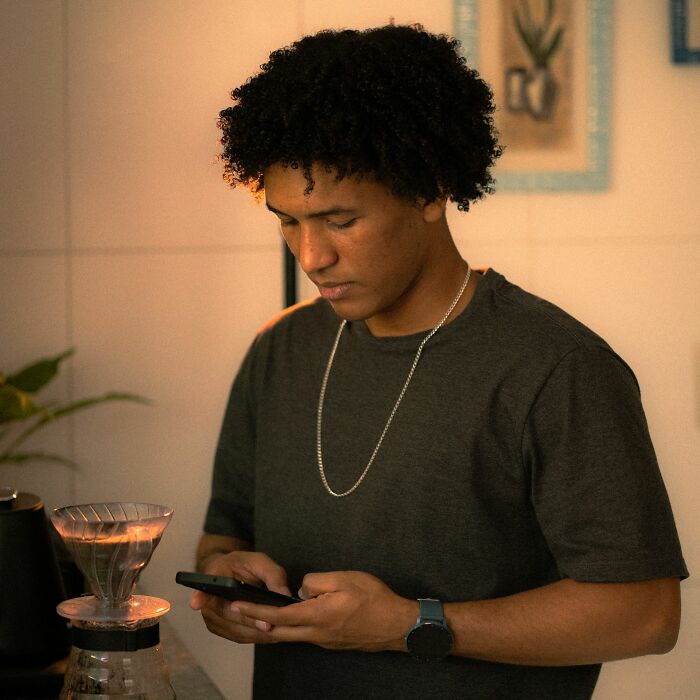 A young man looking at his phone, pondering major life decisions like a walked away marriage.