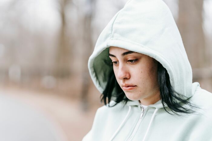 Sad woman in light green hoodie looking down with secrets folks keep hidden.