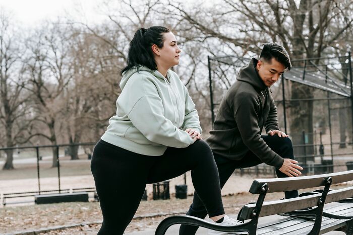 Woman stretching with trainer in outdoor fitness park