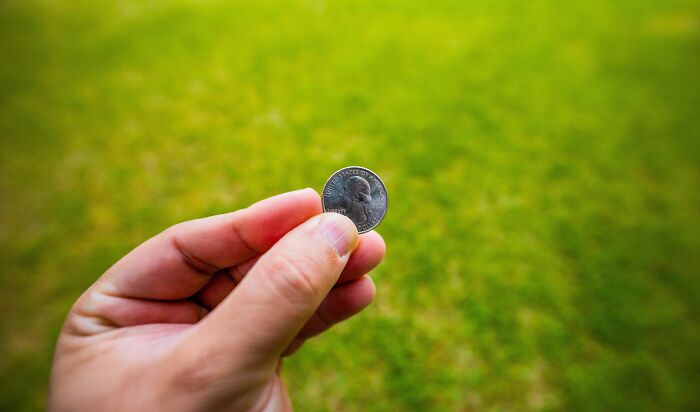 Hand holding a quarter coin representing quiet secrets folks take to the grave.