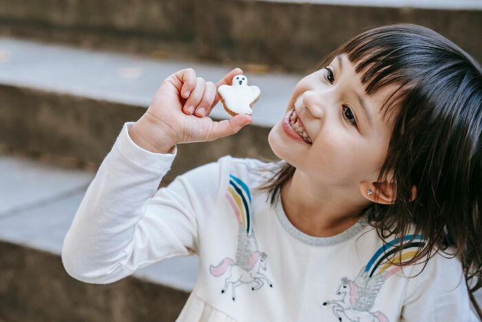 A happy young girl holding a ghost cookie while trick-or-treating