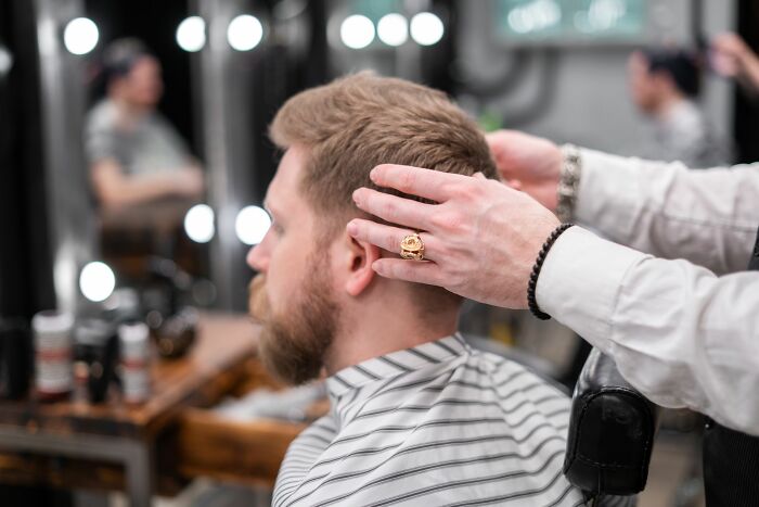 Barber styling a man's hair, showcasing men who care about their appearance after they walk away.