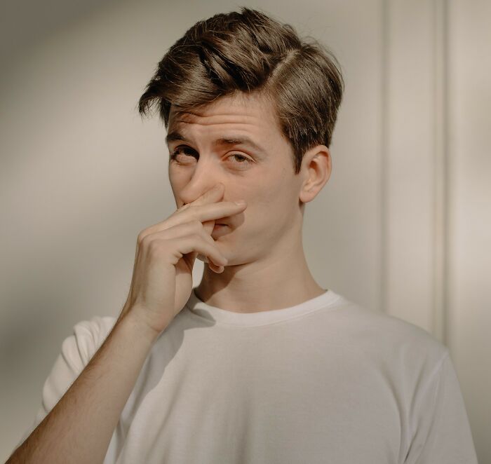 Man pinching nose in reaction to unpleasant smell