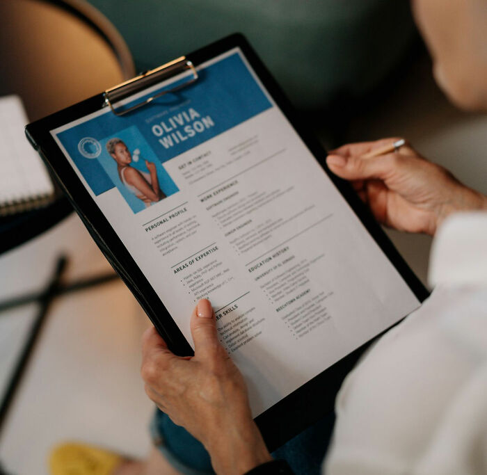 A person holding a resume on a clipboard showcasing clever life tricks for career success