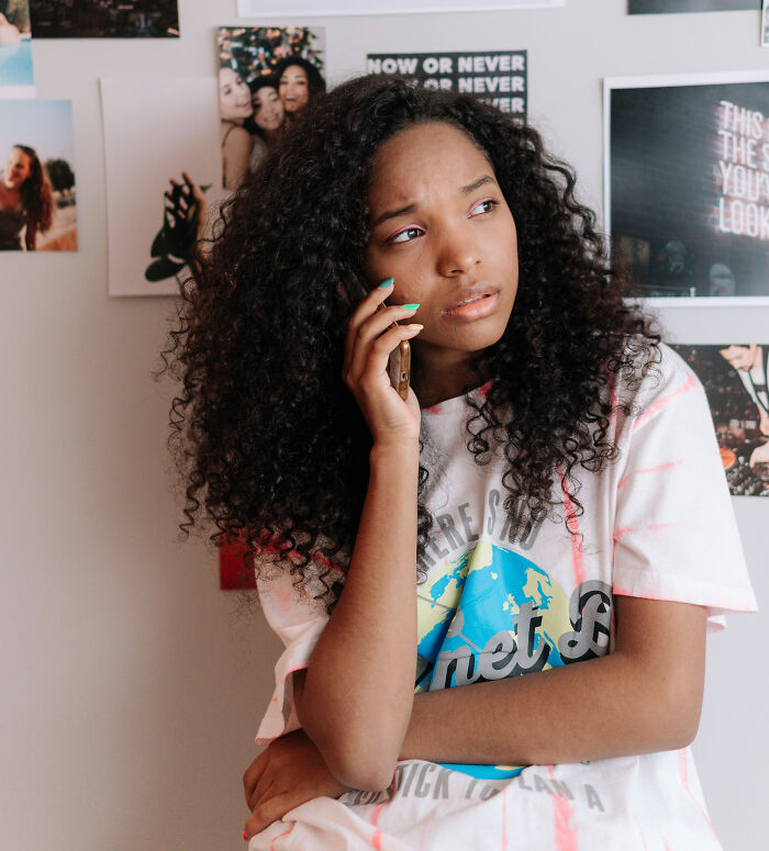 Young woman thoughtfully talking on phone indoors