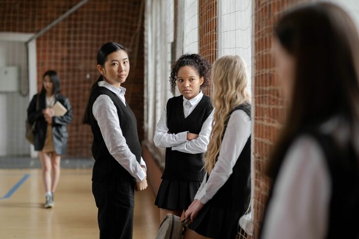 A group of students looking at another student in a school hallway, illustrating classic Hollywood movie tropes.