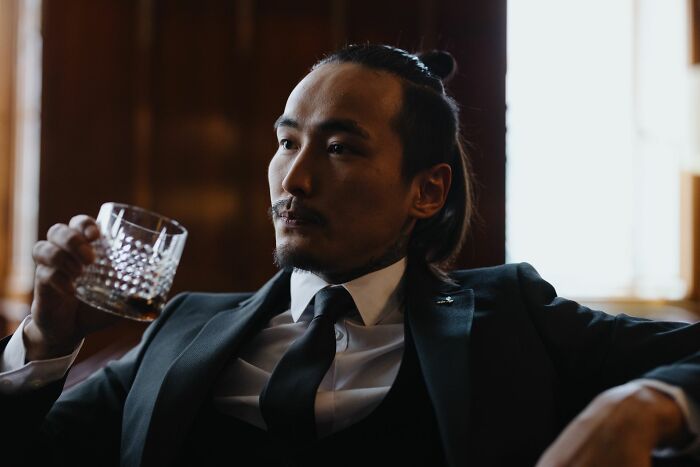 A pensive man in a suit holding a glass of whiskey, reflecting on why men walked away from their marriage.