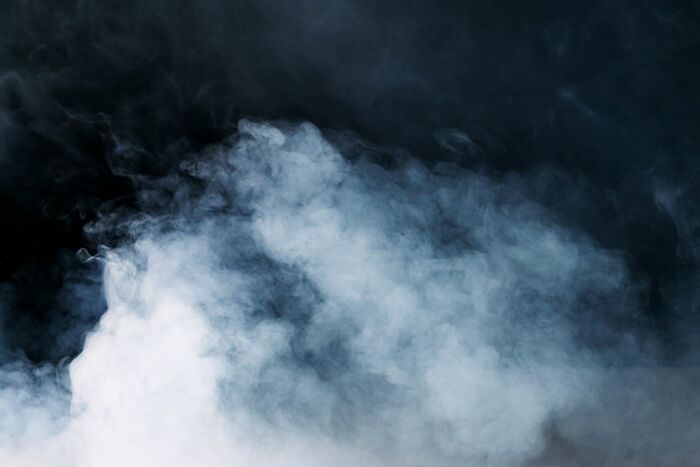 Thick white smoke rising dramatically against a dark background