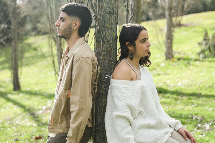 A distant couple standing back-to-back near a tree, representing men who walked away from their marriage.