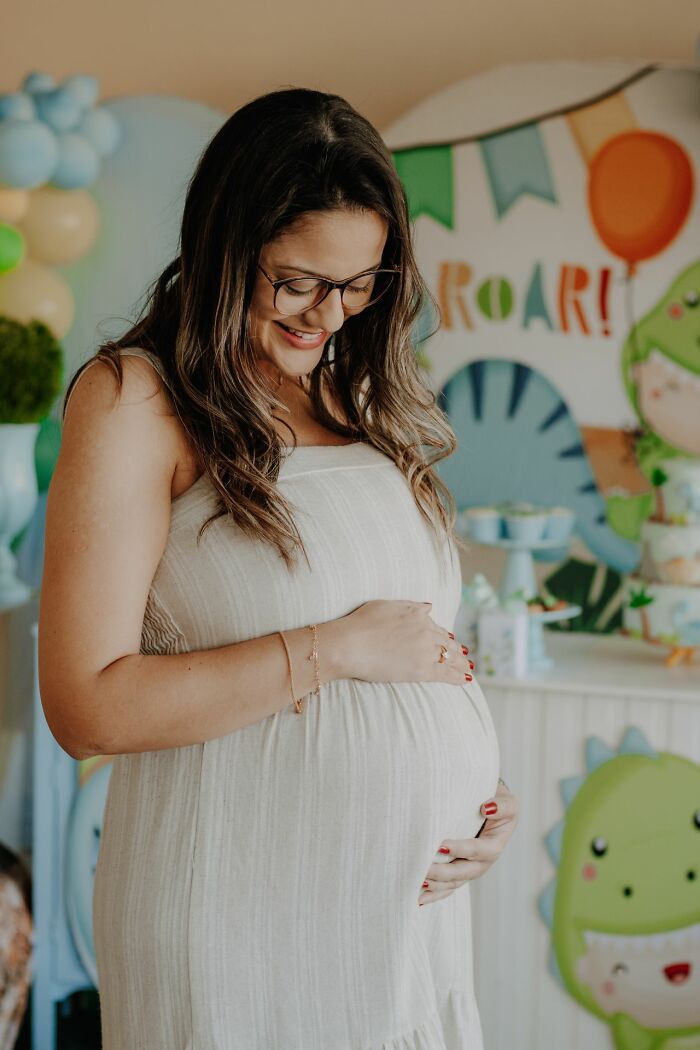 A smiling pregnant woman holding her bump, a lighthearted moment among funny instances when folks failed.