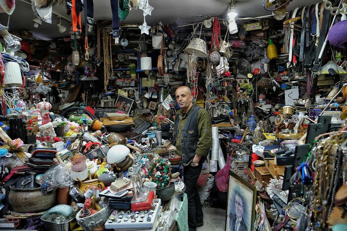 Cluttered house filled with hoarded items and a man standing amidst the mess