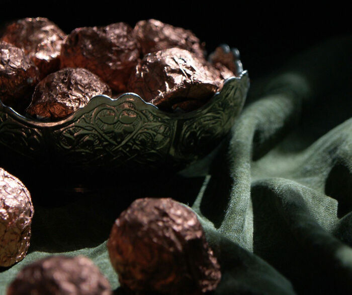 Foil-wrapped chocolates displayed in a decorative bowl given out during trick-or-treating.