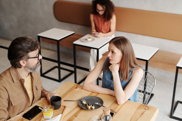 Unhappy couple having a tense conversation in a cafe, hinting they might walk away from marriage