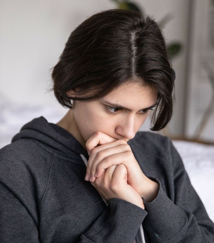 Worried woman with short dark hair in hoodie looking down thoughtfully. Things women wish someone explained.