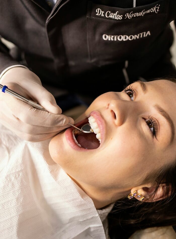 A dentist checking a patient teeth with a dental mirror as part of clever life tricks for personal care.