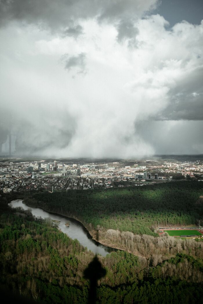 A massive storm cloud approaching a city, invoking an urgent feeling to leave immediately