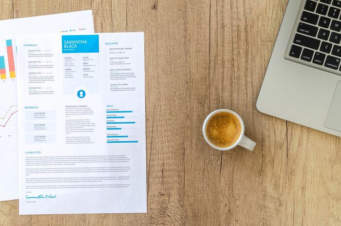 Resume and coffee cup beside laptop depicting professional unhinged things to get back at ex