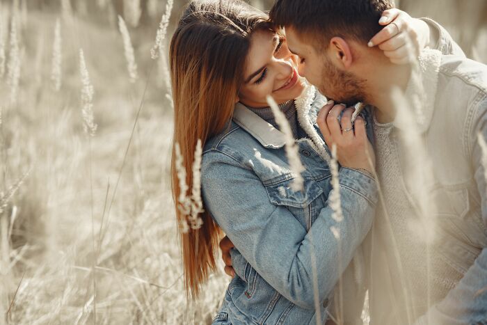 Romantic couple kissing in a field, showing Hollywood romance tropes.